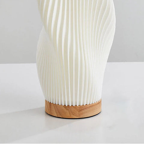 White textured vase with wooden base on a white surface
