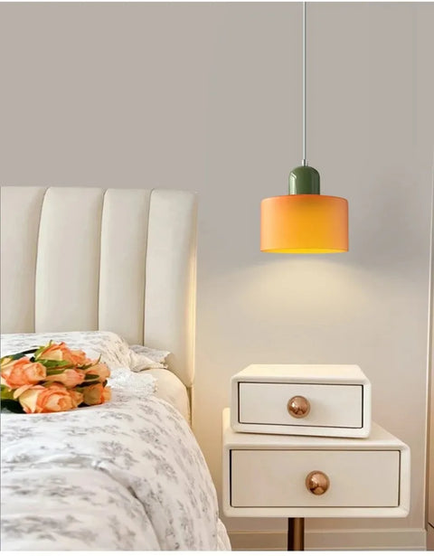 Amber glass pendant light switched on above a bedside cabinet