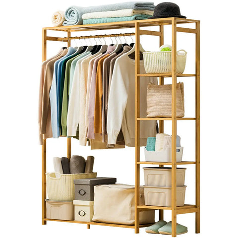 Bamboo garment rack with curtain in gold, holding hanging clothes
