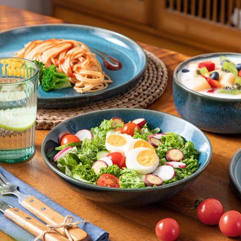 Teal reactive glaze bowls of salad and pasta on a table