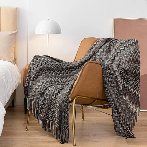Black boho tasselled throw over a tan leather chair
