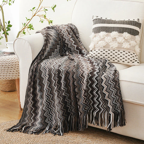 Black boho tasselled throw draped over a white sofa