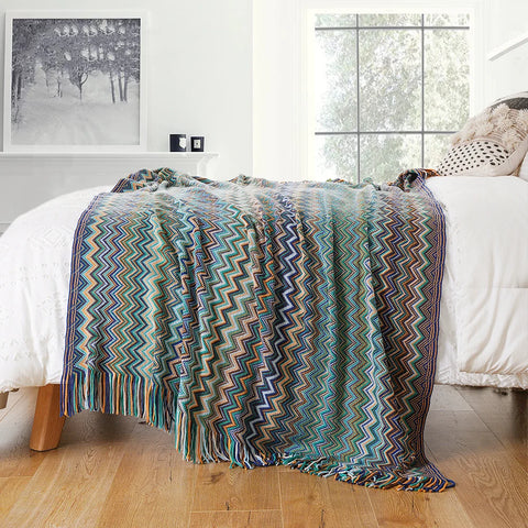 Blue boho tasselled throw across the end of a bed