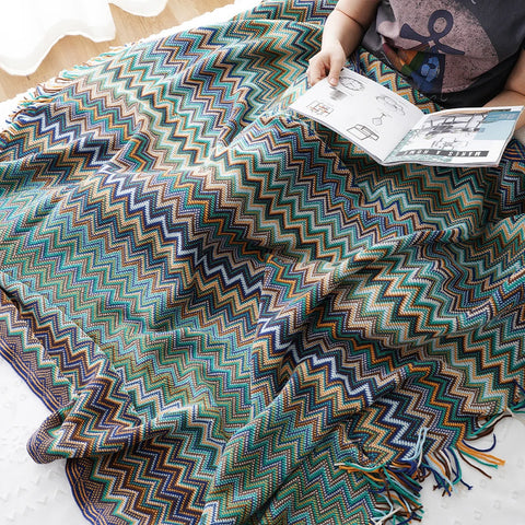 Blue boho tasselled throw over a lap while reading