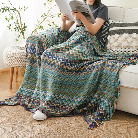 Woman reading on a sofa under a blue boho tasselled throw