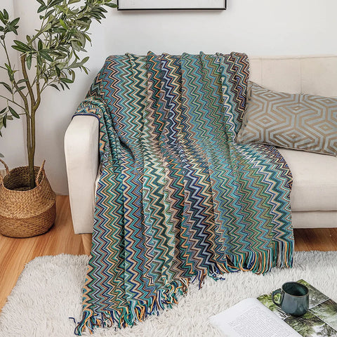 Blue boho tasselled throw on a white sofa beside a plant