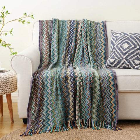 Blue boho tasselled throw draped over a white sofa