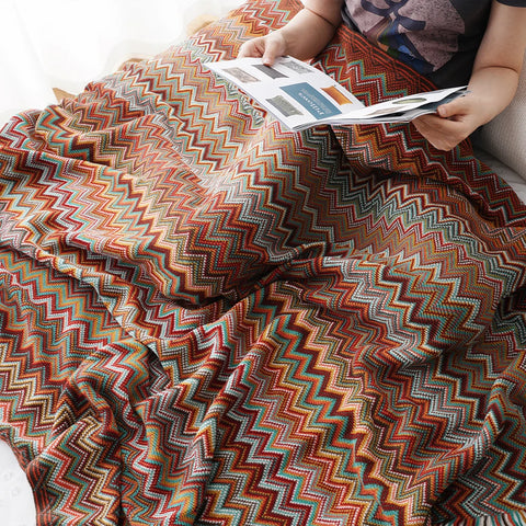 Dusty red boho tasselled throw over a lap while reading