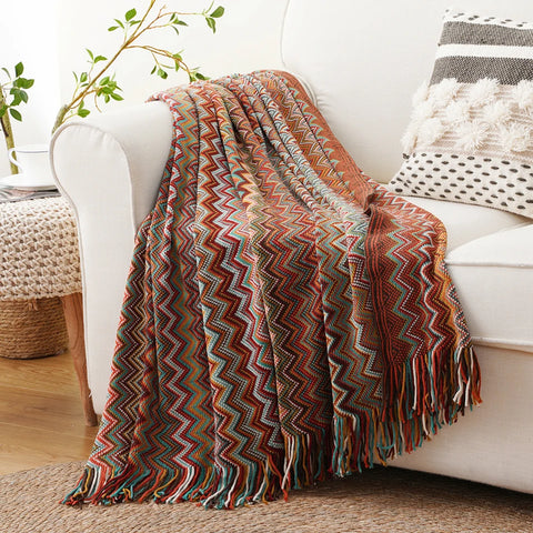 Dusty red boho tasselled throw over the arm of a white sofa