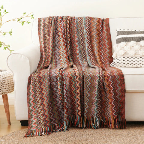 Dusty red boho tasselled throw draped over a white sofa