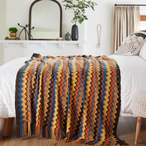 Orange boho tasselled throw across the end of a bed
