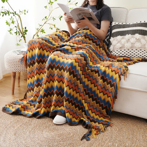 Woman reading on a sofa under an orange boho tasselled throw
