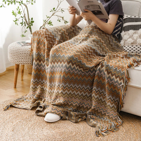 Woman reading on a sofa under a mustard boho tasselled throw