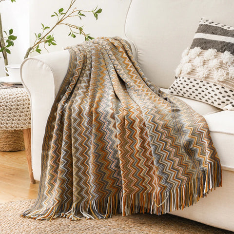 Mustard boho tasselled throw over the arm of a white sofa