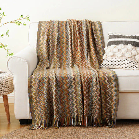 Mustard boho tasselled throw draped over a white sofa
