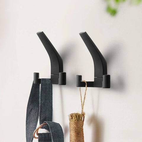 Black brushed metal wall hooks holding a bag