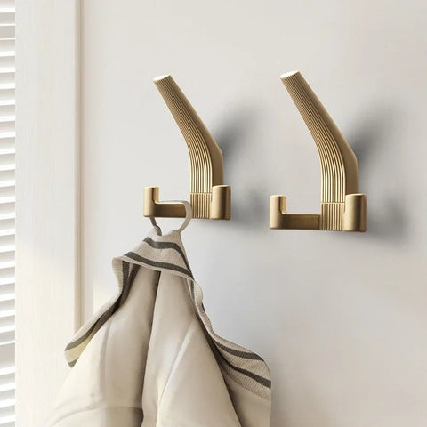 Brushed brass wall hooks holding a dressing gown