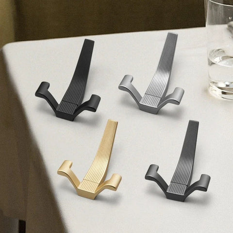 Row of brushed metal wall hooks in black, silver and brass