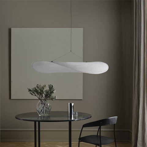 Cloud pendant light above a round black dining table with a vase of dried stems