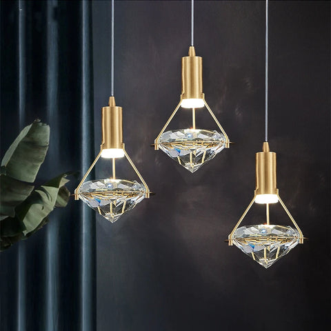 Three copper and crystal pendant lights against a dark green wall