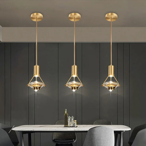 Three copper and crystal pendant lights hung in a row over a dining table