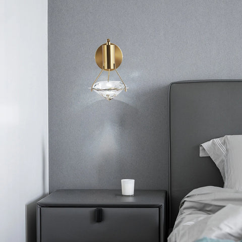Copper and crystal wall light beside a bed