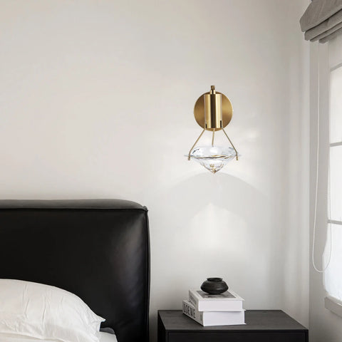 Copper and crystal wall light above a bedside table