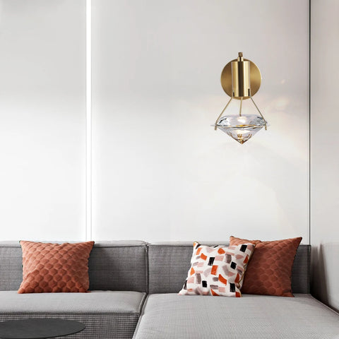 Copper and crystal wall light above a sofa with cushions