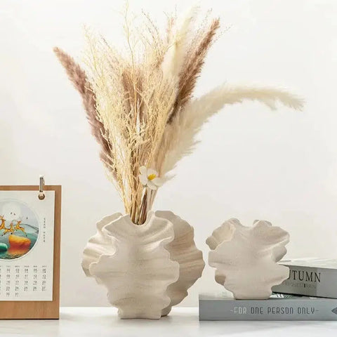 Two Coral ceramic vases holding pampas grass on a shelf