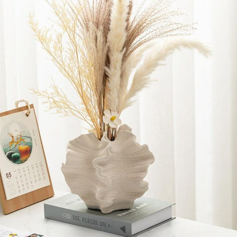 Coral ceramic vase holding pampas grass on a stack of books