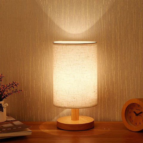 Cylinder bedside lamp lit on a bedside table