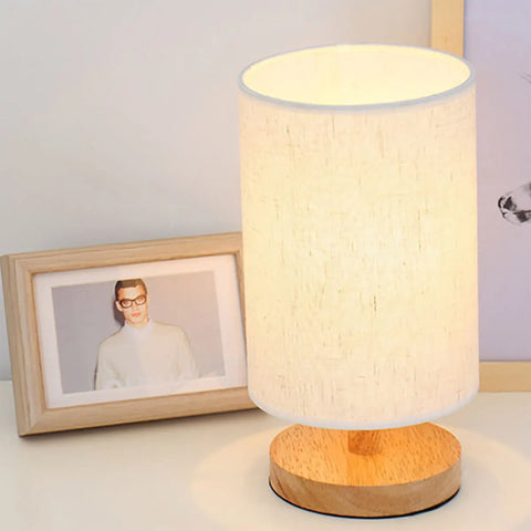 Cylinder bedside lamp lit beside a framed photo