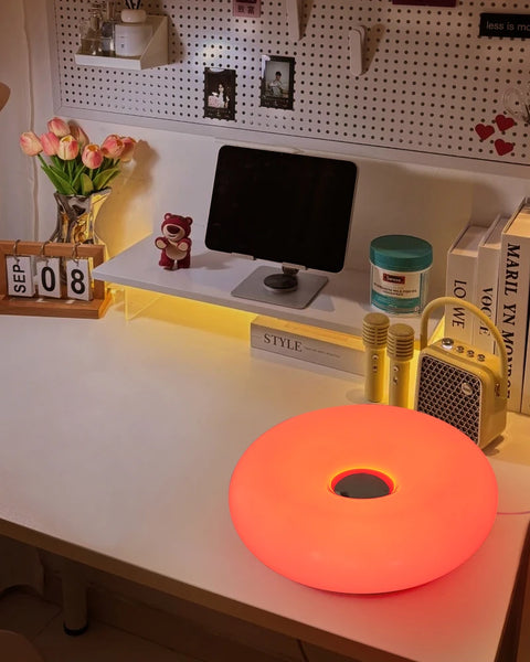 Donut table lamp lit on a desk beside a monitor