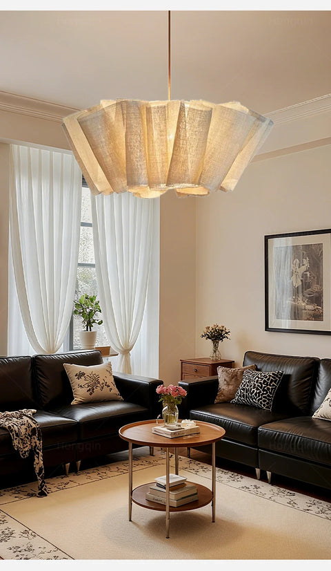 Pleated fabric chandelier above a dark sofa and coffee table