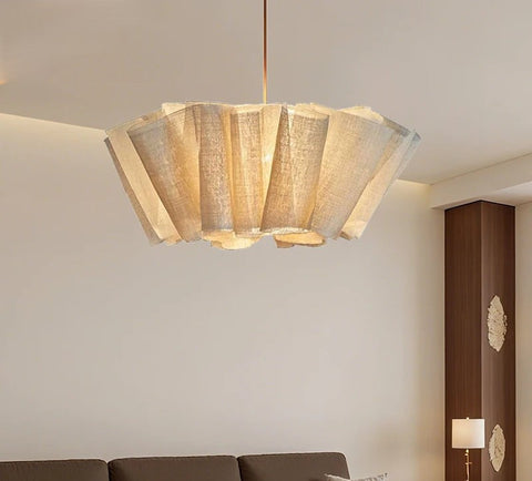 Pleated fabric chandelier lit in a neutral living room