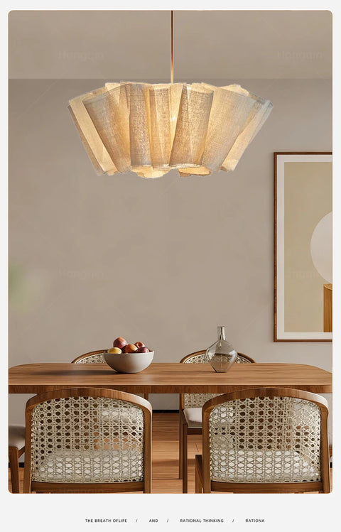 Pleated fabric chandelier above a dining table with rattan chairs