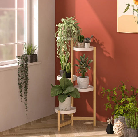 Four-tier bamboo plant stand holding potted plants in a warm room corner