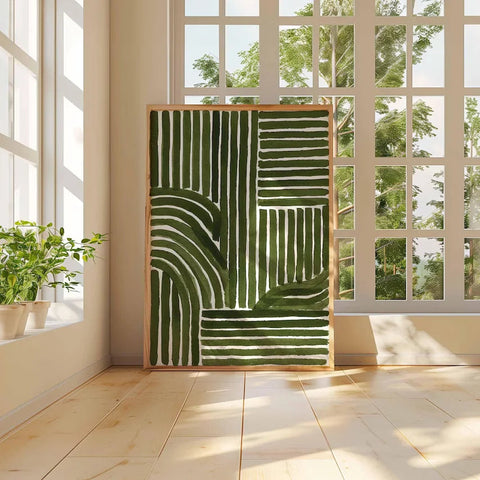 Abstract green and white artwork on a wall with large windows and plants.