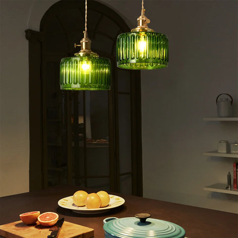 Green glass pendant light lit in a dining space