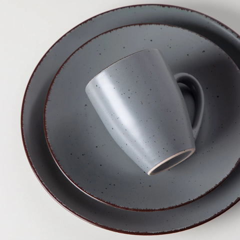 Grey stoneware mug resting on a plate, close view of the glaze