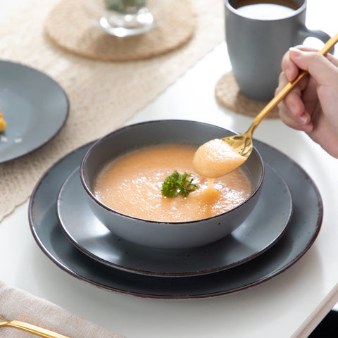 Grey stoneware bowl of soup with a gold spoon