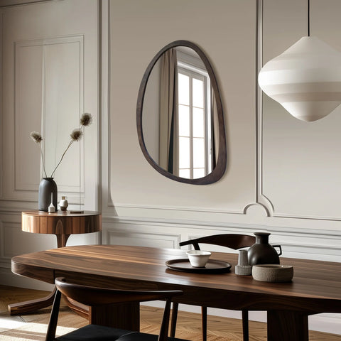 Irregular walnut wall mirror on a wall beside a dining table