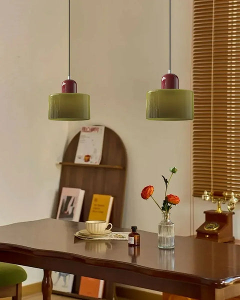 Pair of khaki glass pendant lights with oxblood caps over a dining table