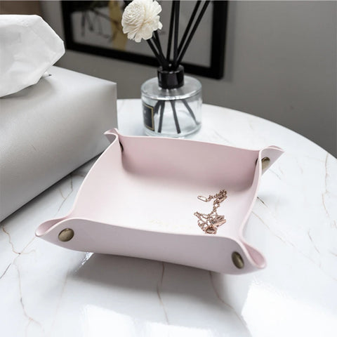 Pink leather valet tray with a reed diffuser and jewellery
