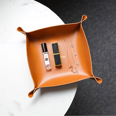 Tan leather valet tray holding a pen and a watch