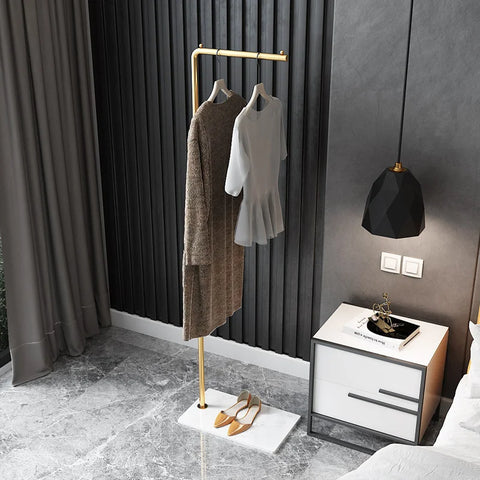 Gold metal valet stand hung with clothes in a bedroom