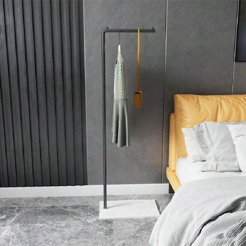 Gold valet stand beside a bed holding a jacket