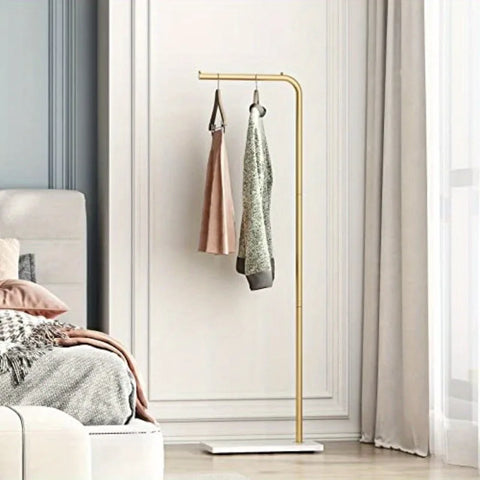 Gold valet stand beside a window with a jacket and scarf