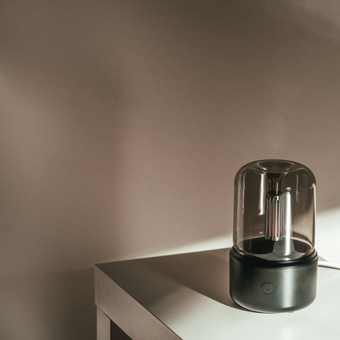 Black Mistt aroma diffuser lit on a desk edge in a dimly lit room