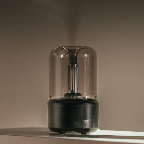 Mistt aroma diffuser in black with the filament lamp lit on a wooden table